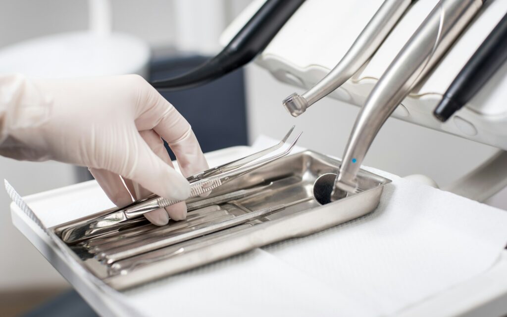 Dentist with gloved hand is picking dental tool in dental office